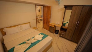 Una habitación de hotel con cama, escritorio, armario y espejo.
