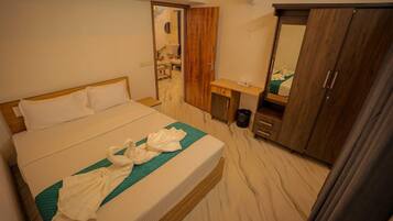 A hotel room with a bed, a desk, a wardrobe, and a mirror.