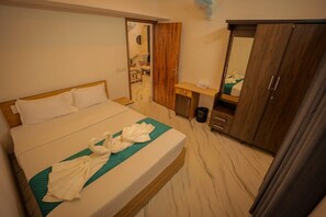Una habitación de hotel con cama, escritorio, armario y espejo.