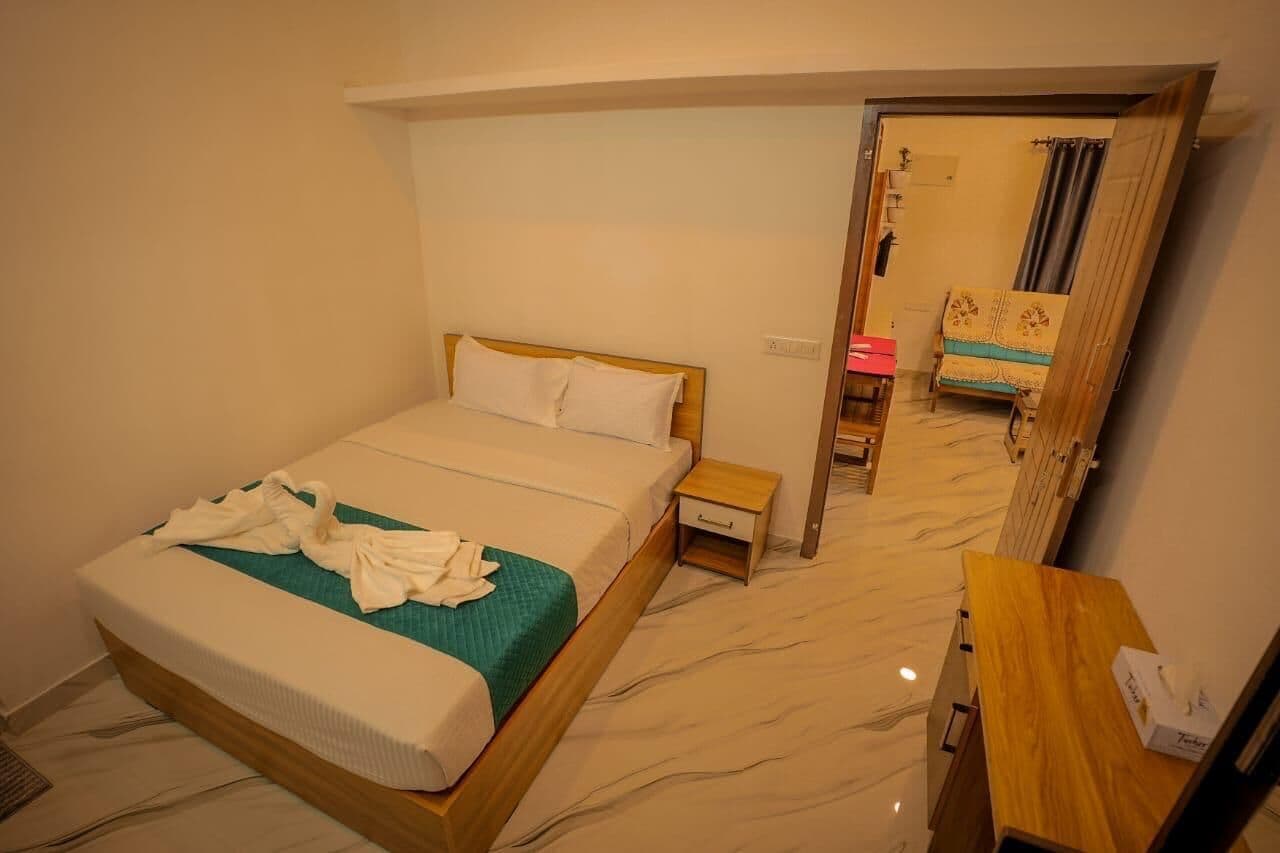 A hotel room with a bed, a bedside table, a desk, and a chair.