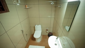Un baño pequeño con inodoro, lavamanos y ducha.