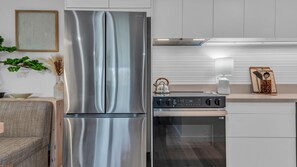 Eine moderne Küche mit Edelstahlgeräten, darunter ein Kühlschrank und ein Backofen, sowie ein Essbereich mit einer Couch und einem Tisch.