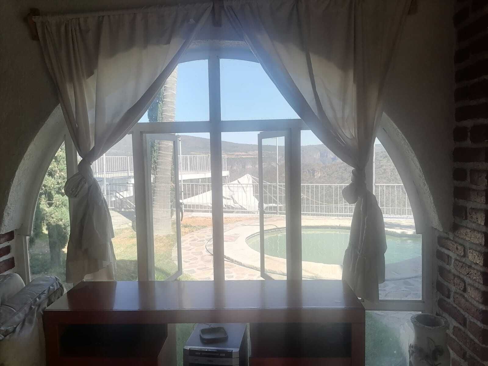 Ein Zimmer mit einem großen Bogenfenster, einem Schreibtisch mit Drucker sowie Blick auf einen Pool und Außenbereich.