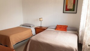 A room with two beds, a nightstand with a lamp, and a framed picture on the wall.
