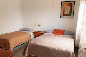 A room with two beds, a nightstand with a lamp, and a framed picture on the wall.
