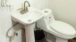 Een badkamer met een wit wastafelmeubel, een toilet en een spiegel aan de muur.