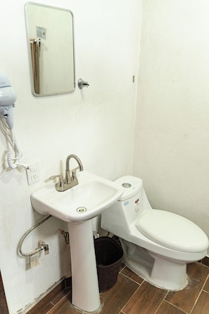 A bathroom with a white sink, a toilet, and a mirror on the wall. - Vrbo Property (Tonalá)