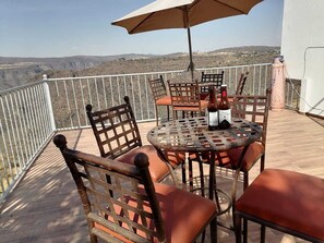 A terrace with a table and chairs, an umbrella, and a view of the landscape. - Vrbo Property (Tonalá)