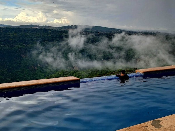 A person in a pool with a mountainous landscape in the background. - Vrbo Property (Tonalá)