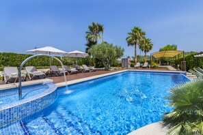 A swimming pool with lounge chairs and umbrellas, surrounded by greenery and palm trees. - Grand Majorcan Retreat With Pool (Pollença)