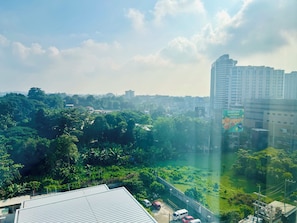 Un paisaje urbano con abundante vegetación, un rascacielos y un cielo despejado.