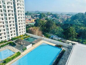 A residential building with a rooftop swimming pool, surrounded by greenery and other buildings. - Studio Suite Condo at the Avida Towers Abreeza in vibrant Davao City (Davao City)