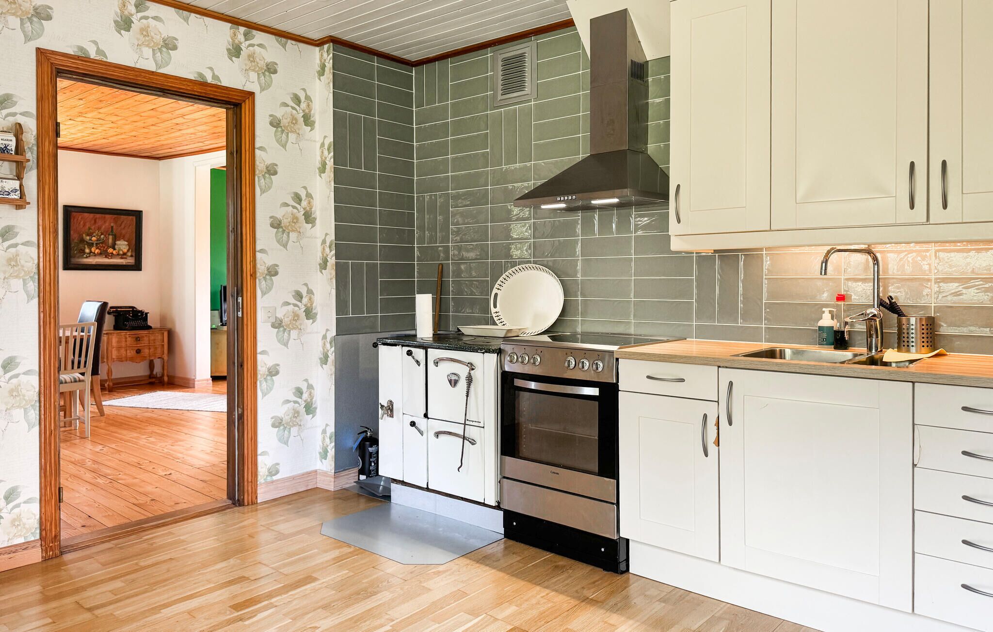 A modern kitchen with a built-in oven, a stove, and white cabinets.