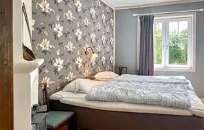 A bedroom with a bed, a nightstand, a lamp, a window with curtains, and a view of greenery outside. - Awesome home in Lammhult with WiFi (Lammhult)
