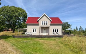 A two-story house with a red roof, a front porch with chairs, and a covered patio area. - Awesome home in Lammhult with WiFi (Lammhult)