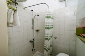 Ein kleines Badezimmer mit Dusche, Toilette und Handtuchhalter.