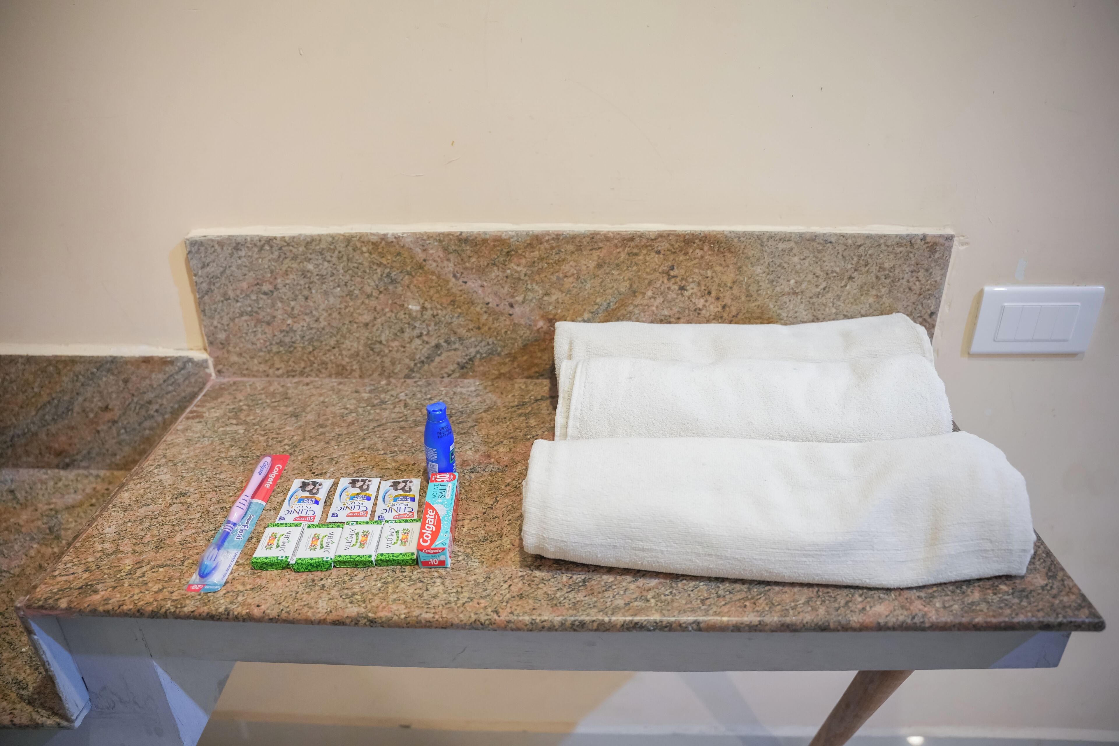 A bathroom counter with a towel, toothbrushes, toothpaste, and a bottle of mouthwash.