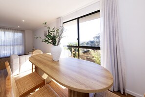 Un comedor moderno con una mesa de madera, sillas tejidas y un jarrón blanco con plantas.