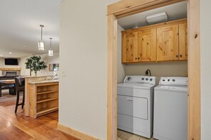 Ein Waschraum mit zwei weißen Waschmaschinen, Holzschränken und einer Spüle mit Arbeitsplatte.