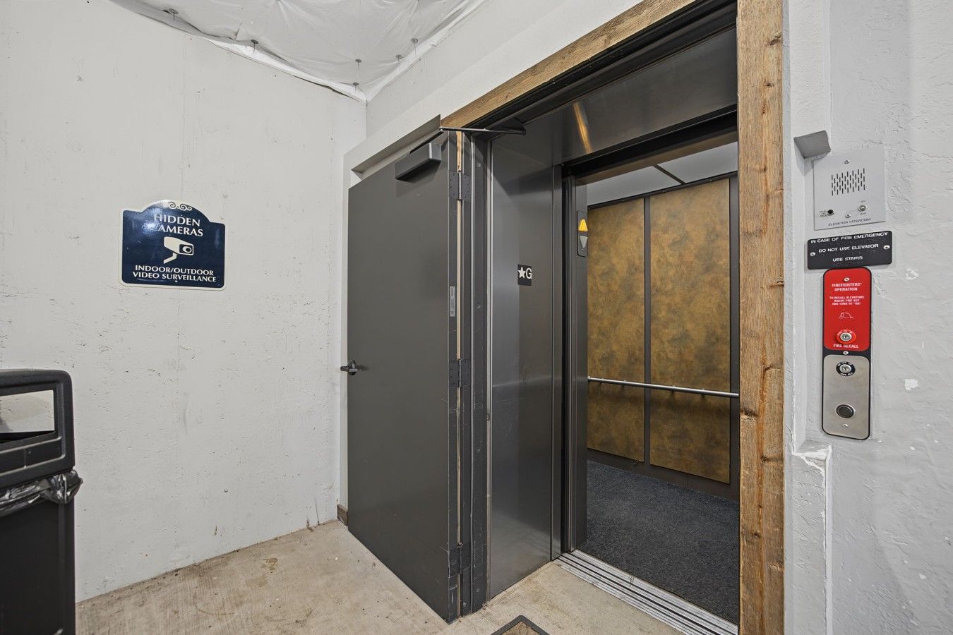 An elevator with a sign indicating video surveillance and emergency instructions.