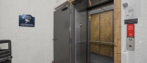 An elevator with a sign indicating video surveillance and emergency instructions.