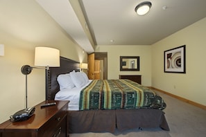 Ein Hotelzimmer mit Bett, Nachttisch, Lampe und einem an der Wand befestigten Spiegel.