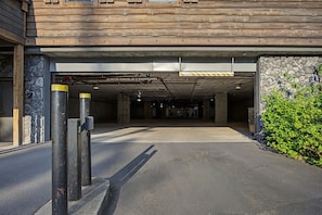 Eingang zu einer Tiefgarage mit einer Steinsäule und einer Holzkonstruktion darüber.