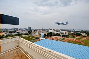 An airplane taking off with a cityscape in the background. - Hotel Airstay Inn (Bandikodegehalli Amanikere)
