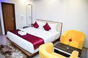 A hotel room with a bed, a bedside table, a chair, and a mirror. - Hotel Airstay Inn (Bandikodegehalli Amanikere)