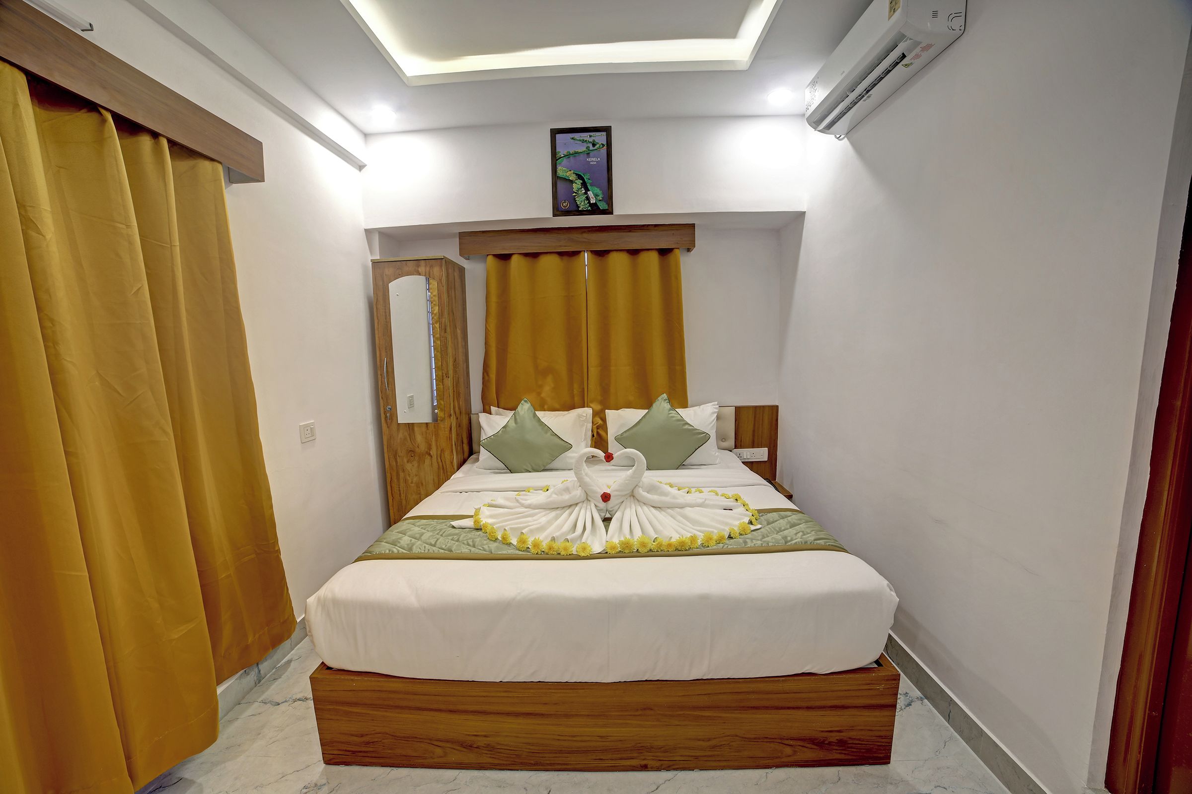 Habitación de hotel con cama, cabecero de madera, un cuadro y una ventana con cortinas.