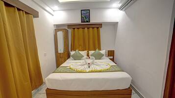 Habitación de hotel con cama, cabecero de madera, un cuadro y una ventana con cortinas.