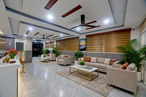Un saló modern amb un conjunt de sofàs, una taula de centre i ventiladors de sostre.