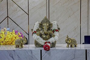 A statue of a deity with intricate designs, surrounded by flowers and placed on a marble surface. - Hotel Airstay Inn (Bandikodegehalli Amanikere)