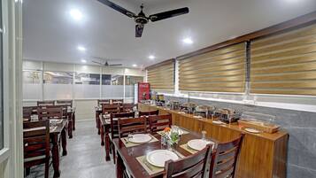 Un área de comedor con mesas y sillas de madera, un mostrador de buffet y un ventilador de techo.