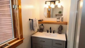 A bathroom with a window, a sink, a mirror, and a towel rack. - Cozy cottage minutes from Okemo Mtn. (Mount Holly)