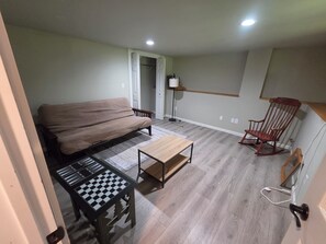 A compact living space with a sofa, a small table, a rocking chair, and a floor lamp.