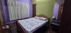 Un dormitorio con cama, cortinas, una puerta y un pequeño banco.