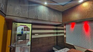 A room with wooden cabinets, a bed with a patterned bedspread, and a red light fixture.