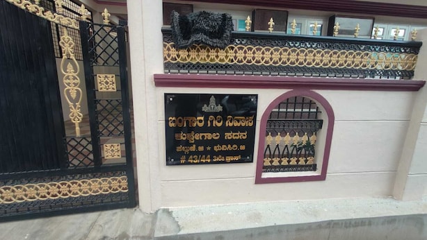 Une façade d’immeuble avec un portail noir, une plaque portant une inscription et des éléments décoratifs.