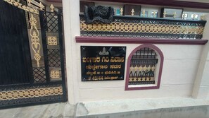 A building facade with a black gate, a plaque with text, and decorative elements.