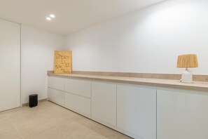 A clean, modern kitchen with white cabinetry, a beige countertop, and a small trash bin. - Villa Llum de Mar - Benissa, Costa Blanca (Benissa)