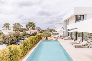 Un espace piscine extérieur moderne, doté de chaises longues et offrant une vue sur le paysage environnant.