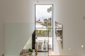 Interior moderno com parede de vidro que dá para uma varanda, um sofá e uma luminária.