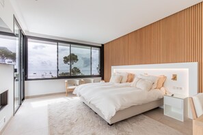 Une chambre moderne avec un grand lit, des tables de chevet et une vue sur la mer.