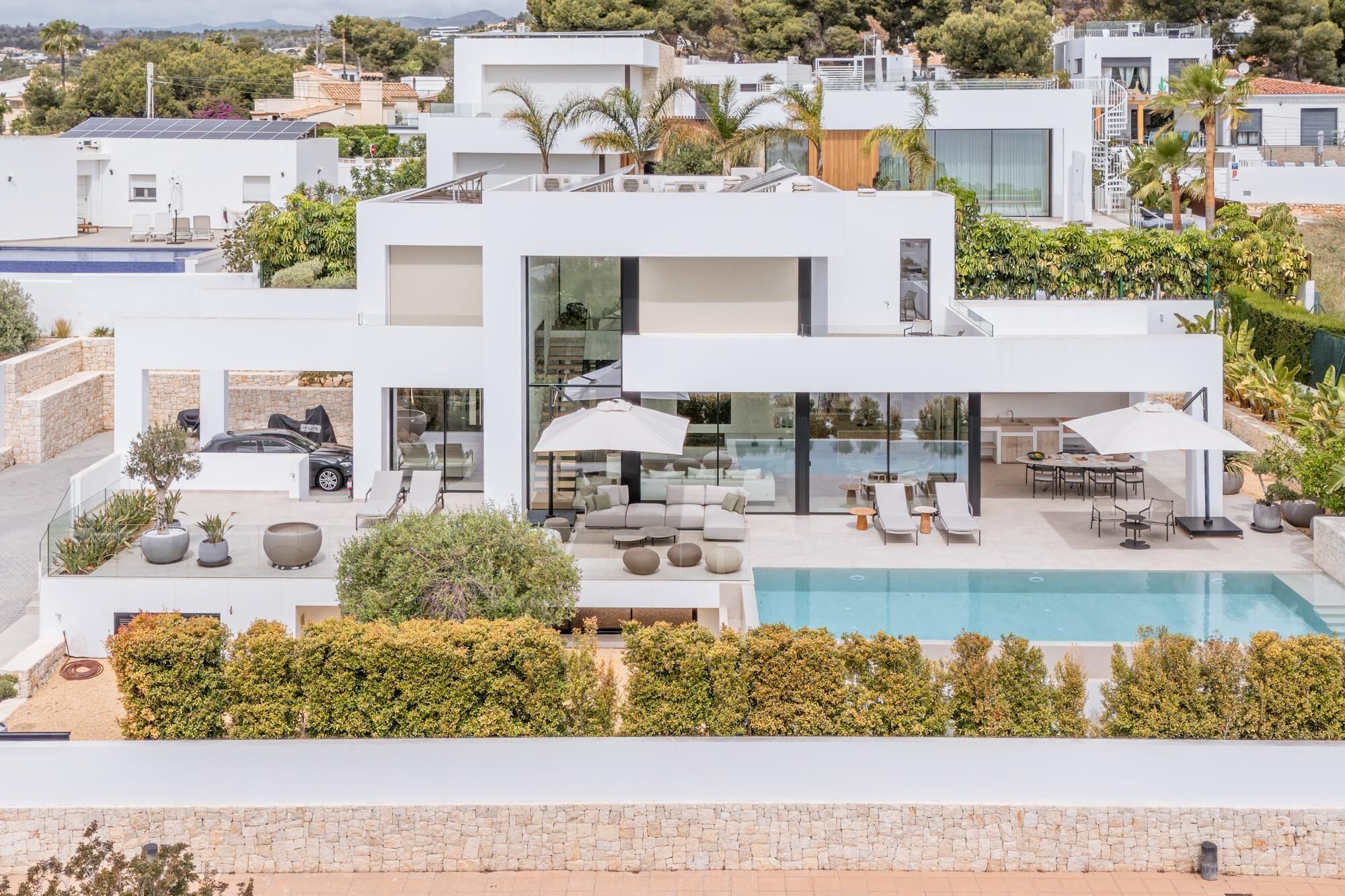 Un immeuble résidentiel moderne à plusieurs étages, doté d’une piscine, d’un espace extérieur aménagé et offrant une vue sur le paysage environnant.