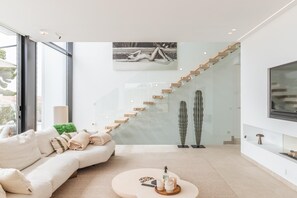 Un salon moderne avec un canapé aux lignes courbes, un escalier en verre et un design minimaliste.