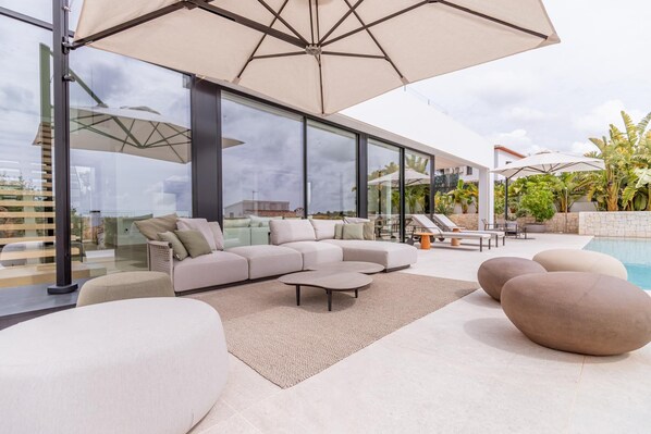 A modern outdoor living area with a sectional sofa, round coffee table, and a pool.
