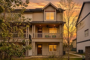 A two-story residential building with a balcony, a front door, and a visible garage door.