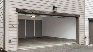 En garageindgang med beton gulv, en metalramme til dør og en lille lampe over døren.