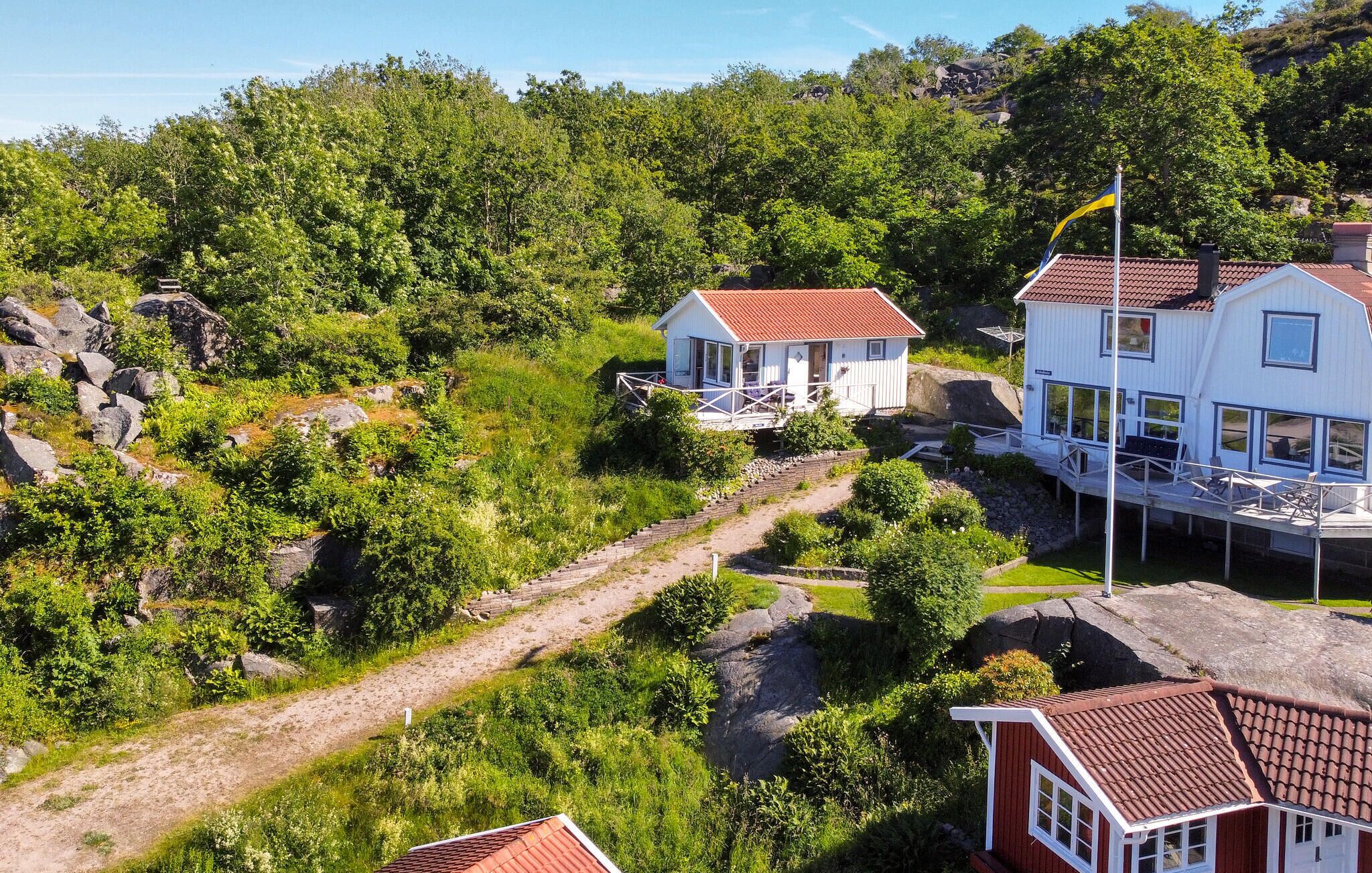 Ein Küsteneigentum mit mehreren Gebäuden, darunter ein Hauptgebäude mit Balkon und ein kleineres Nebengebäude, umgeben von üppiger Vegetation und felsigem Gelände.